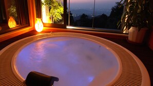 Un jacuzzi con vista a un paisaje urbano al atardecer.