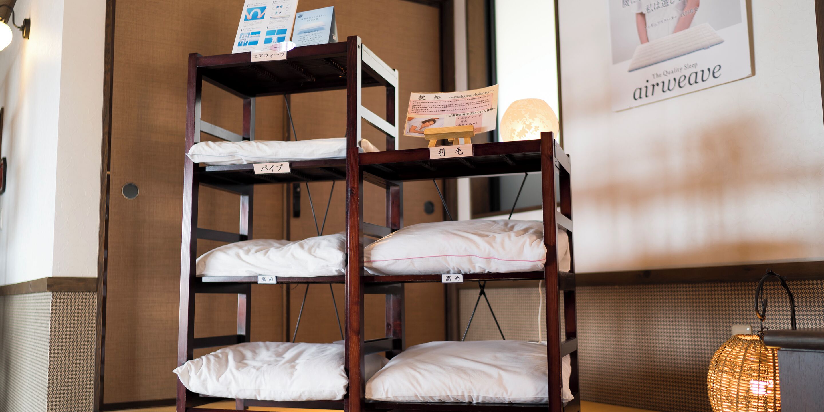 Camas literas con almohadas y etiquetas en una habitación con pared estampada y una lámpara colgante.