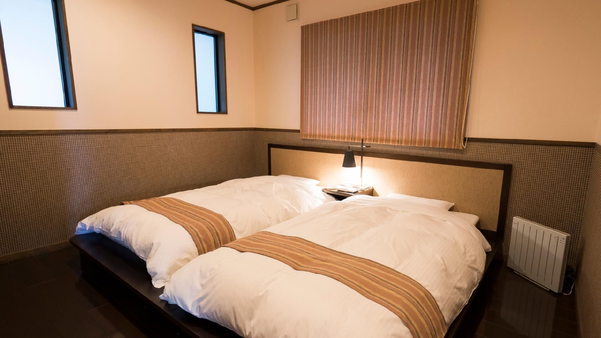 A double bed with a headboard, a bedside table, a lamp, a window, and a radiator.