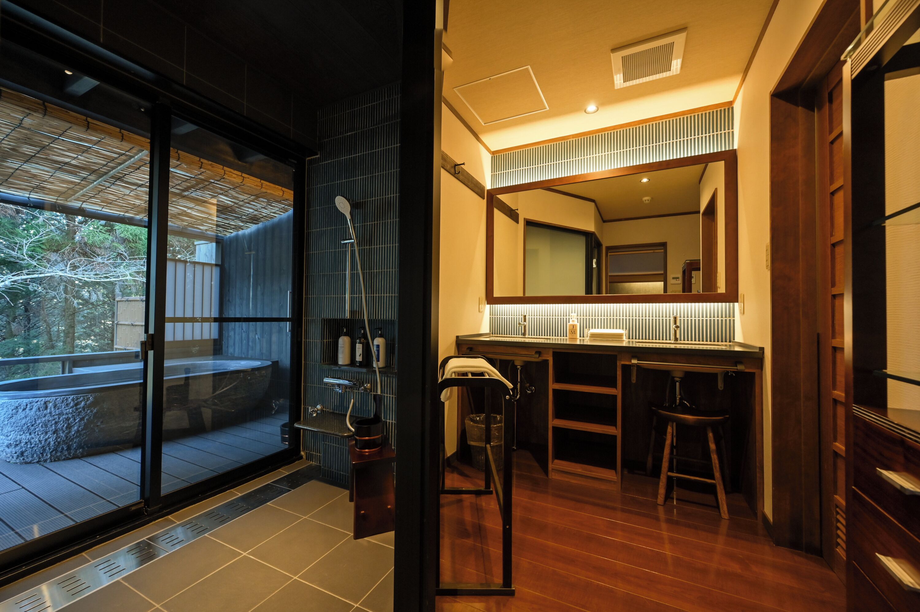 A modern bathroom with a large mirror, wooden vanity, and a glass shower enclosure.