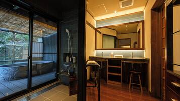 A modern bathroom with a large mirror, wooden vanity, and a glass shower enclosure.