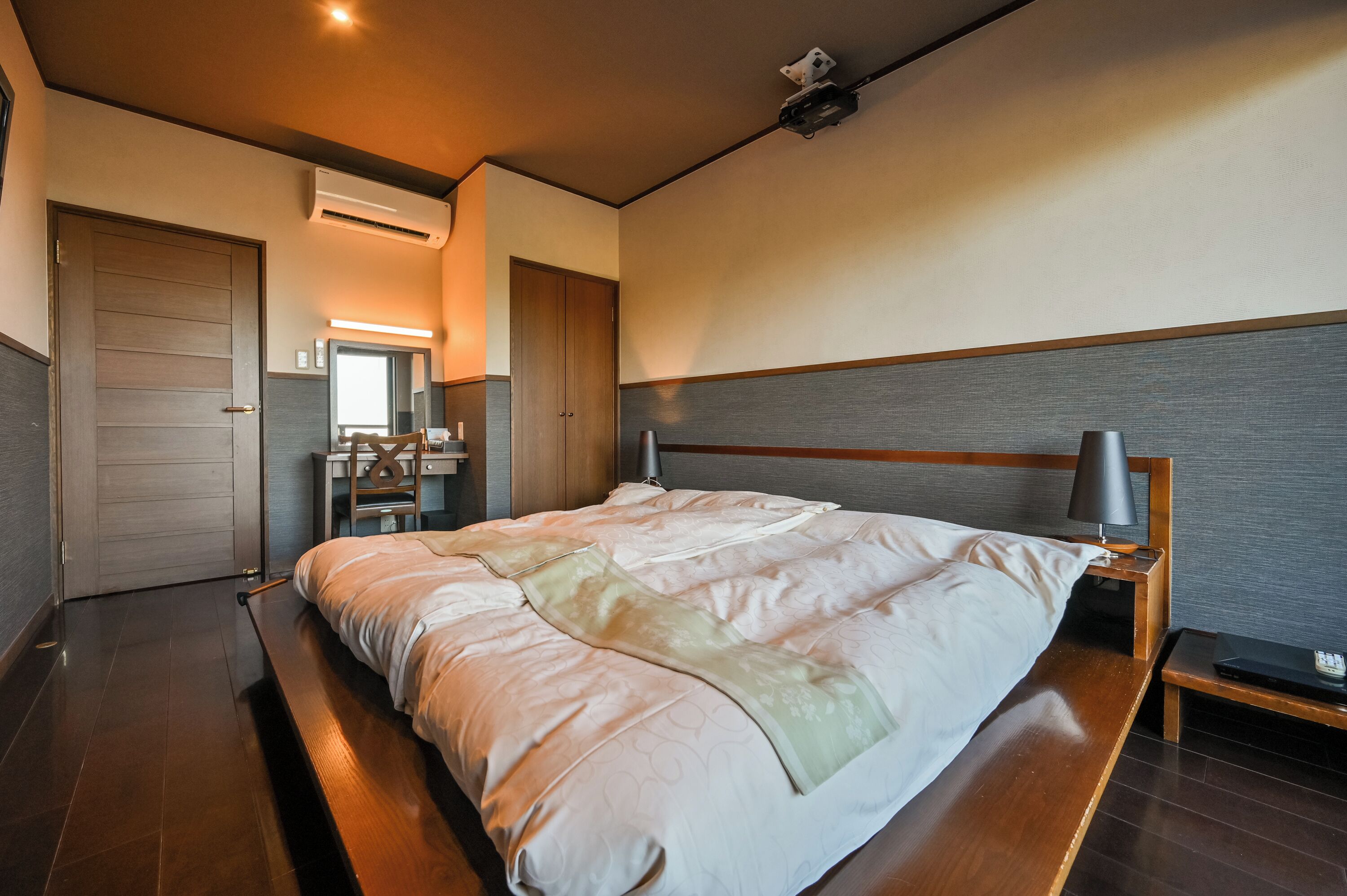 Una habitación de hotel moderna con una cama grande, una mesita de noche y un espejo.