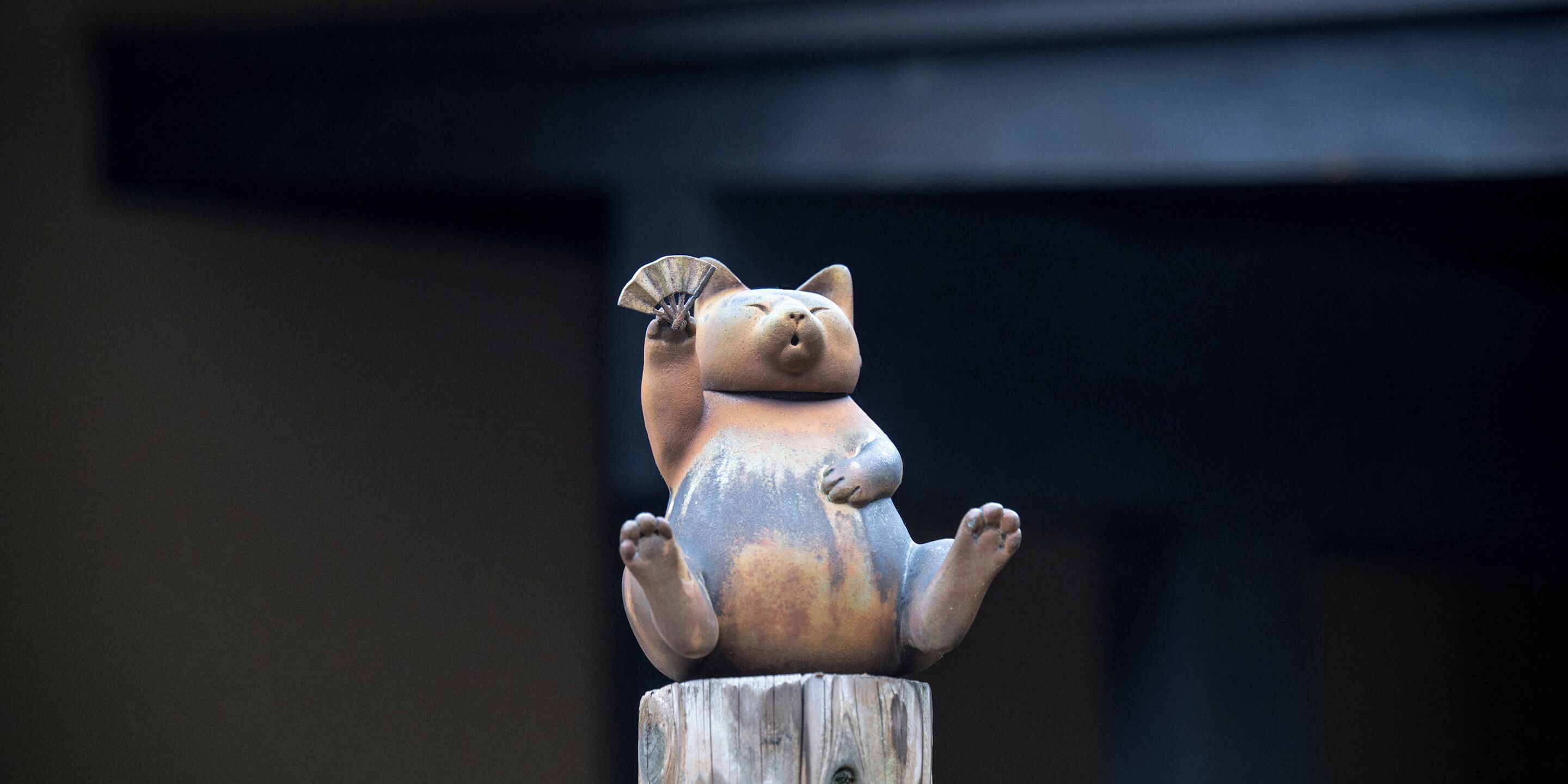 En staty av en katt med en fläkt på huvudet, stående på en trästolpe.