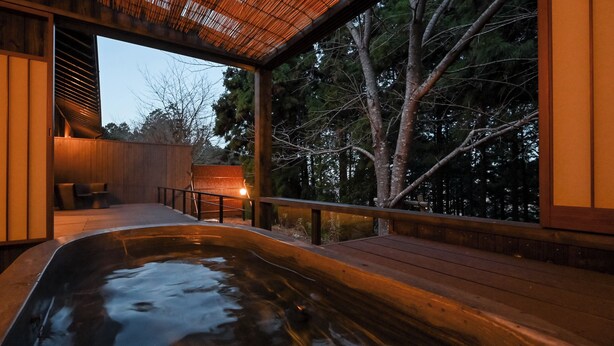 Un área de hidromasaje con una terraza de madera, un espacio para sentarse y vistas a árboles.