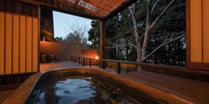 Ein Whirlpoolbereich mit Holzterrasse, Sitzgelegenheit und Blick auf Bäume.