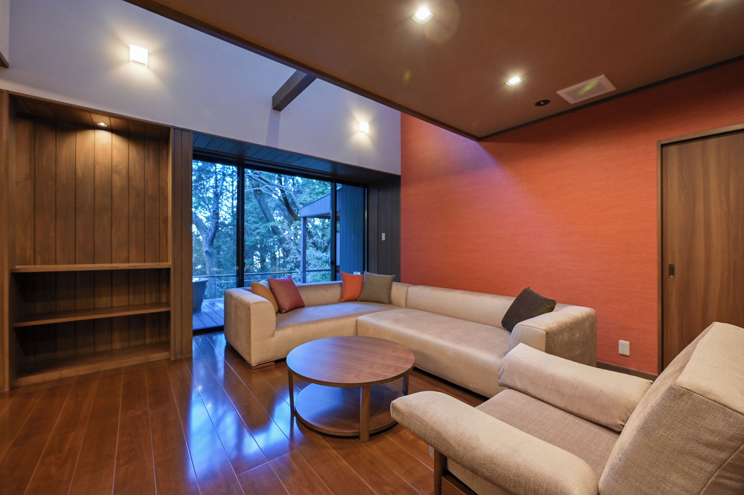 Una sala de estar moderna con un sofá seccional, una mesa de centro redonda y una estantería de madera.