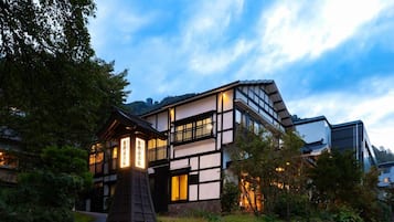 A traditional Japanese building with a modern extension, surrounded by greenery.