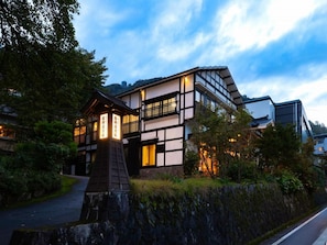 A traditional Japanese building with a modern extension, surrounded by greenery. - Otowaya Ryokan (Yuzawa)