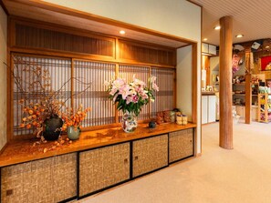 Un'area reception con scrivania in legno, un tradizionale paravento giapponese shoji e un vaso con fiori.