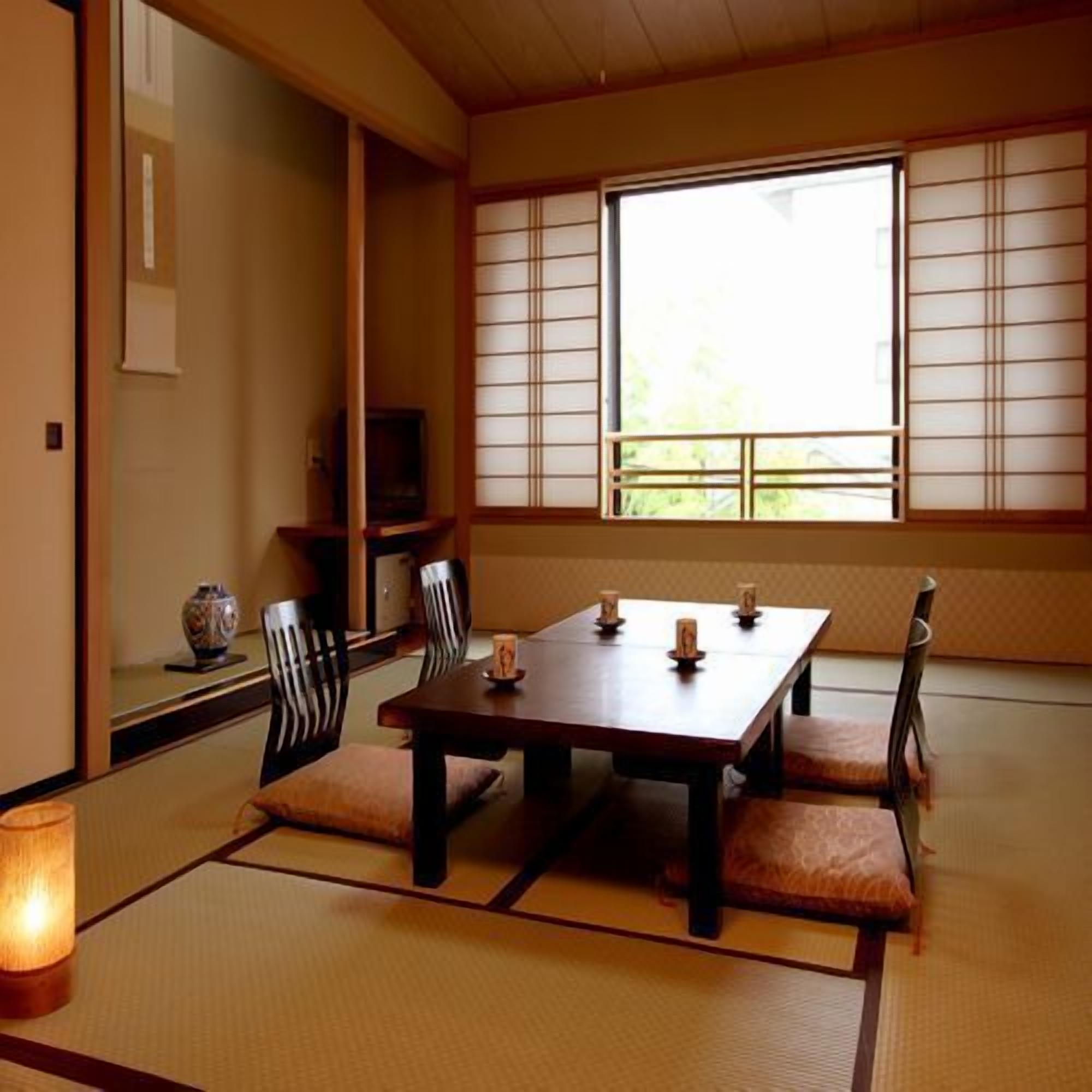 Ein traditioneller japanischer Raum mit Tatami-Boden, einem niedrigen Tisch mit Kissen und einer verschiebbaren Shoji-Trennwand.