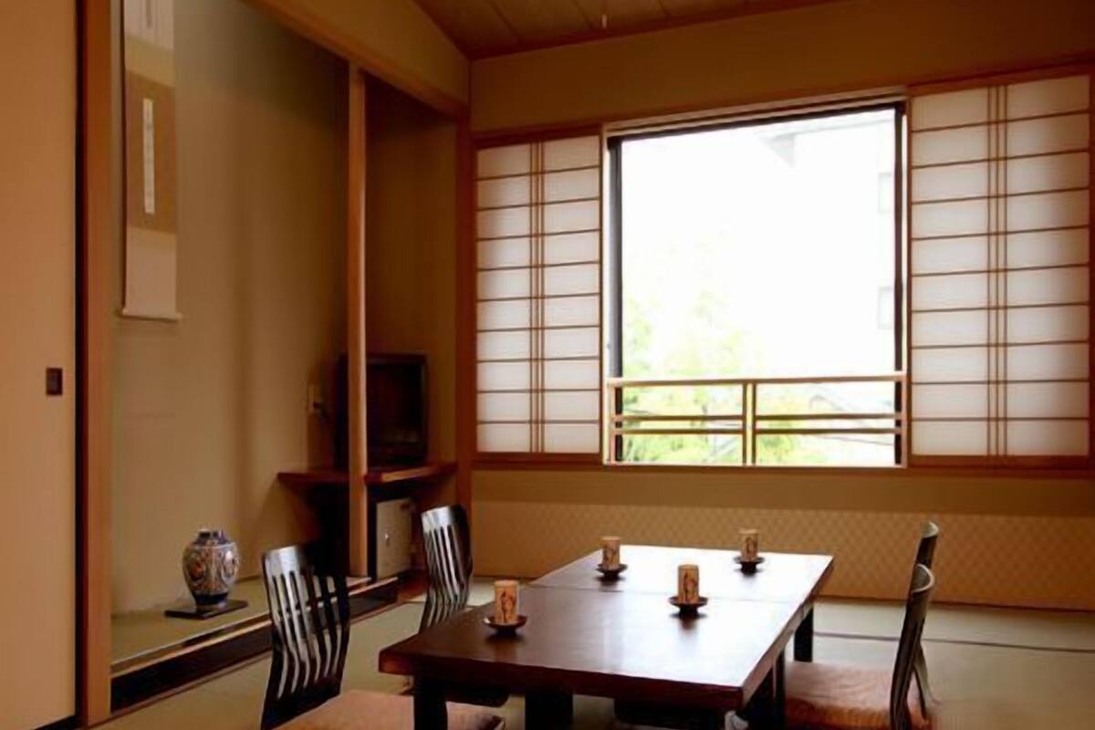 Ein traditioneller japanischer Raum mit Tatami-Boden, einem niedrigen Tisch mit Kissen und einer verschiebbaren Shoji-Trennwand.
