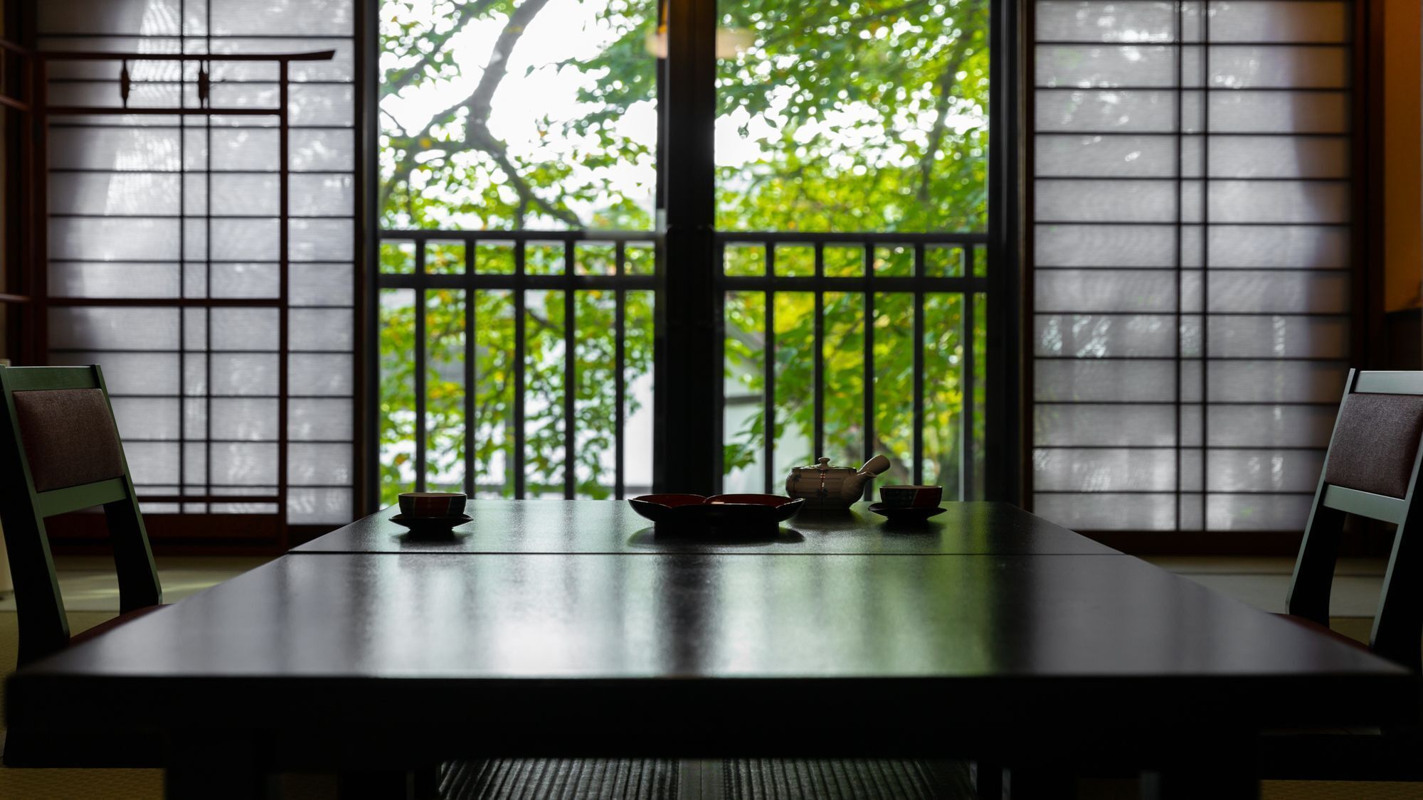 Ein traditioneller japanischer Raum mit Tatami-Böden, einem niedrigen Tisch mit Teeservice und verschiebbaren Shoji-Türen.