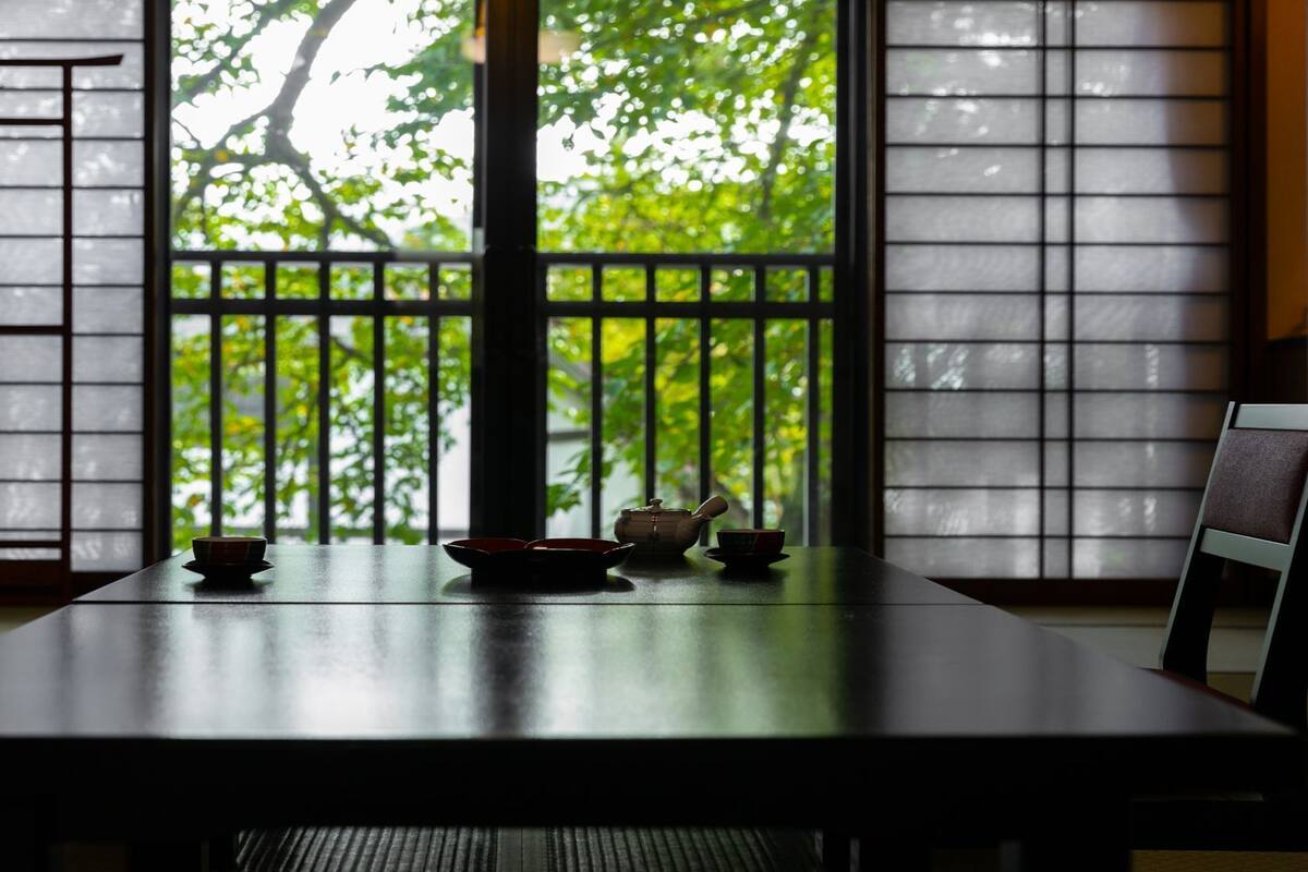 Ein traditioneller japanischer Raum mit Tatami-Böden, einem niedrigen Tisch mit Teeservice und verschiebbaren Shoji-Türen.