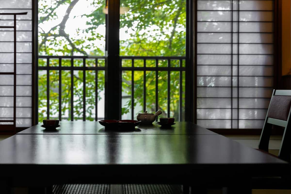 Una habitación tradicional japonesa con suelo de tatami, una mesa baja con juego de té y puertas correderas shoji.