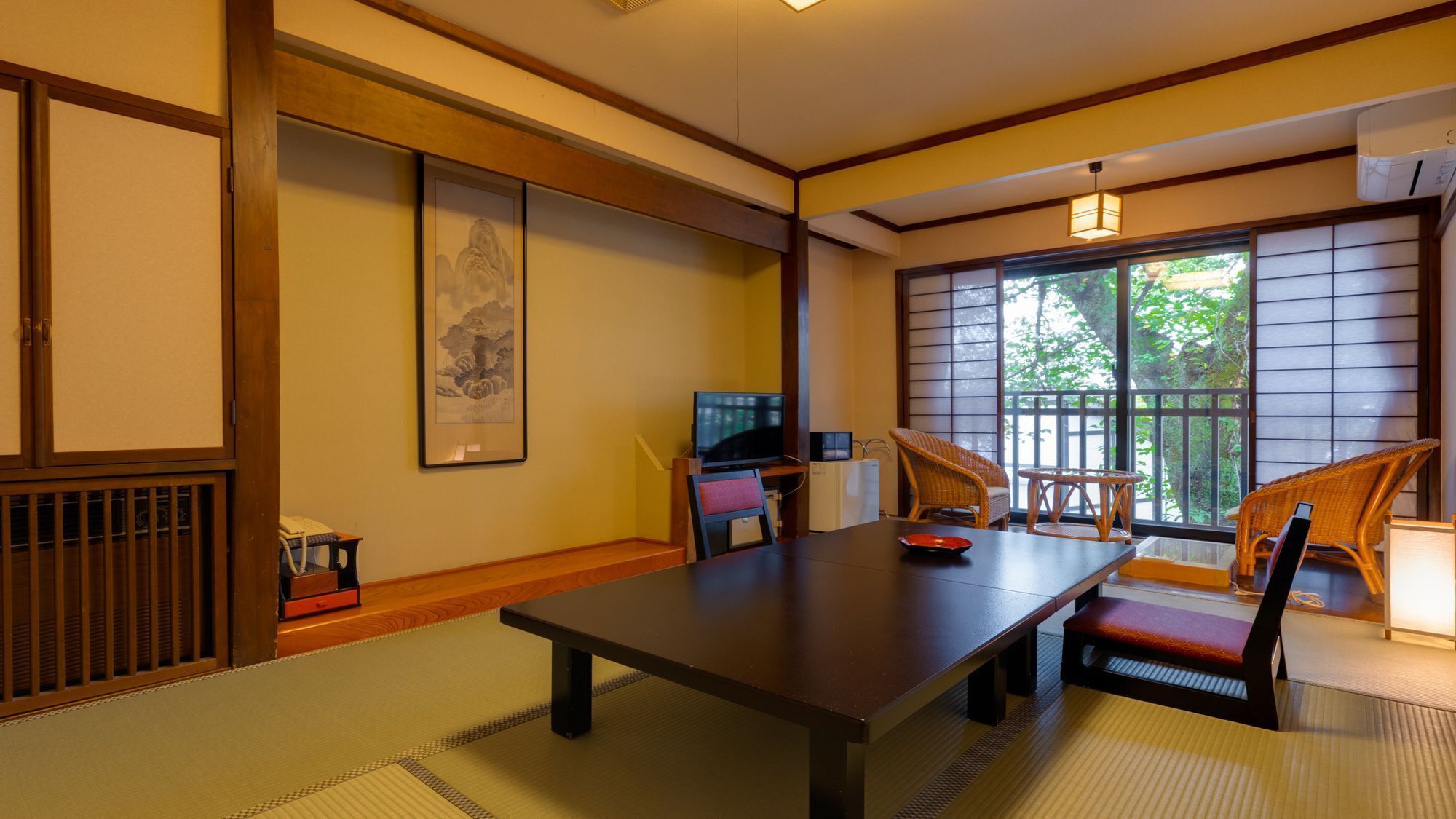 Ein traditioneller japanischer Raum mit Tatami-Boden, einem niedrigen Tisch und einem Fernseher.