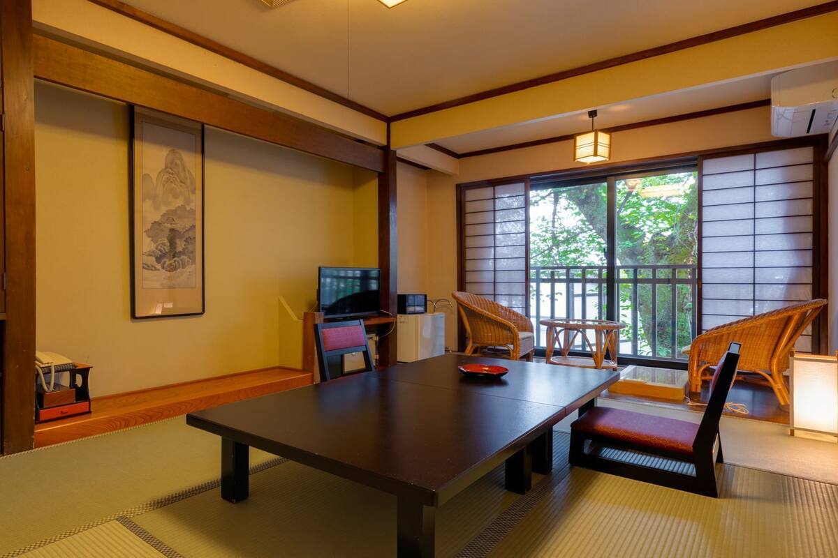 Ein traditioneller japanischer Raum mit Tatami-Boden, einem niedrigen Tisch und einem Fernseher.