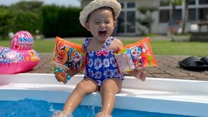 Un niño sentado en una piscina sosteniendo bolsas de comida.