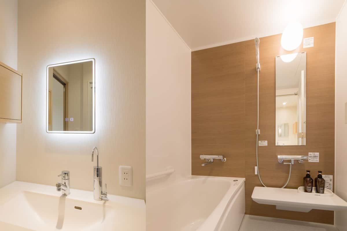 Un baño moderno con un espejo grande, una bañera y un lavabo.