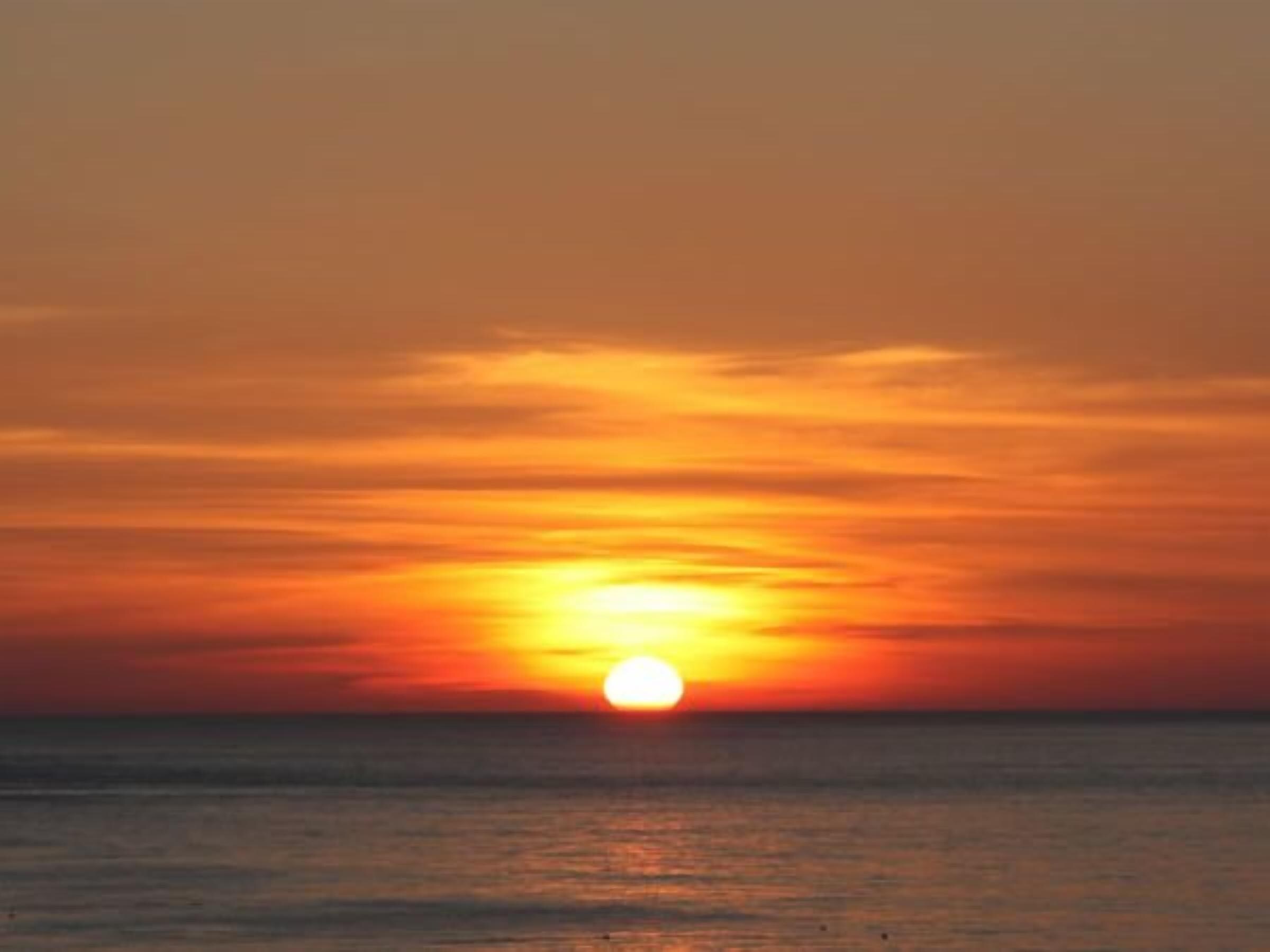 Un coucher de soleil sur l’océan, avec un ciel dégagé.