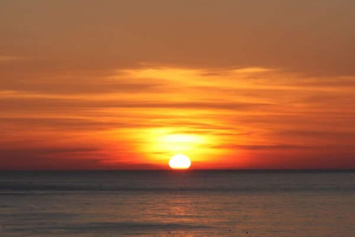 Un atardecer sobre el océano bajo un cielo despejado.