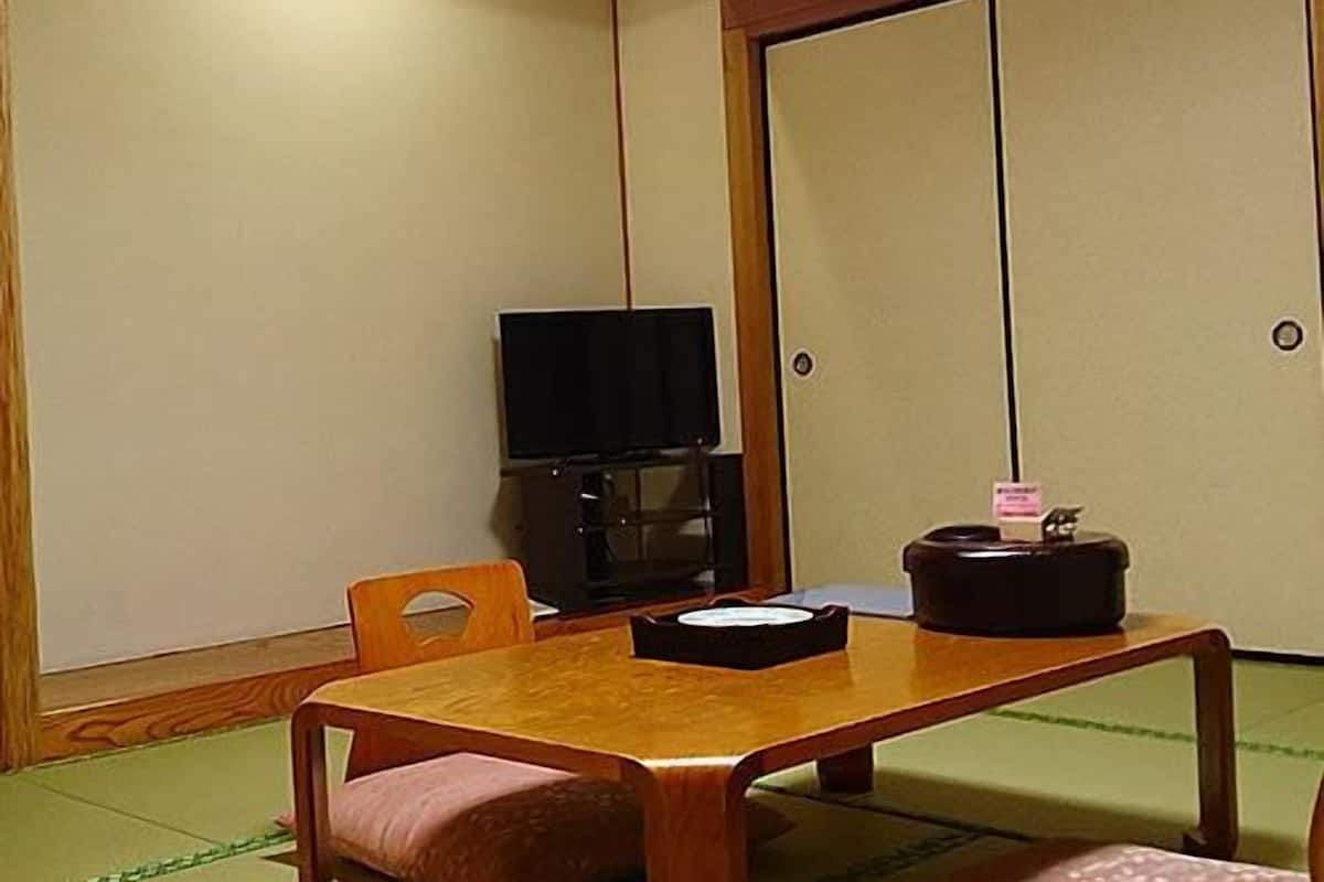 Una habitación con una mesa de madera, un televisor y una puerta corredera.