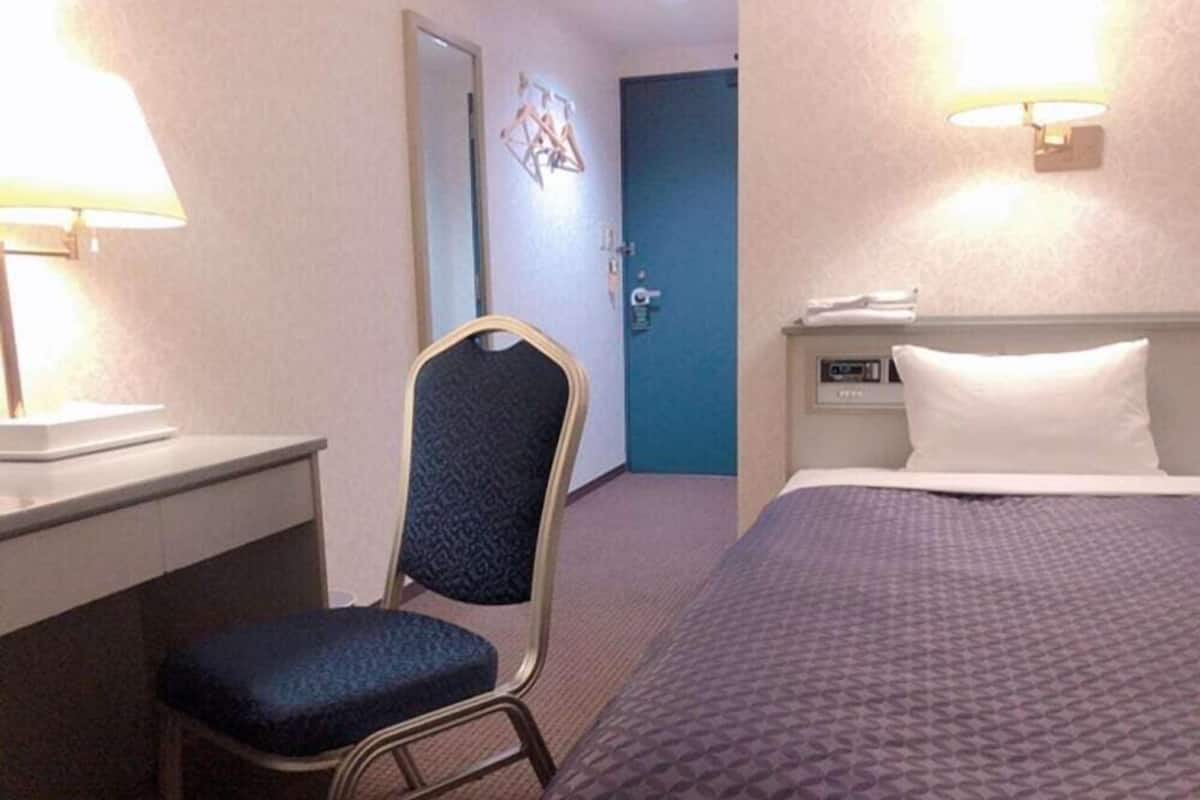 Una habitación de hotel con cama, escritorio, silla y puerta.