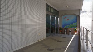 Passadís amb parets i terra de rajola, que condueix a una porta d'entrada de vidre.
