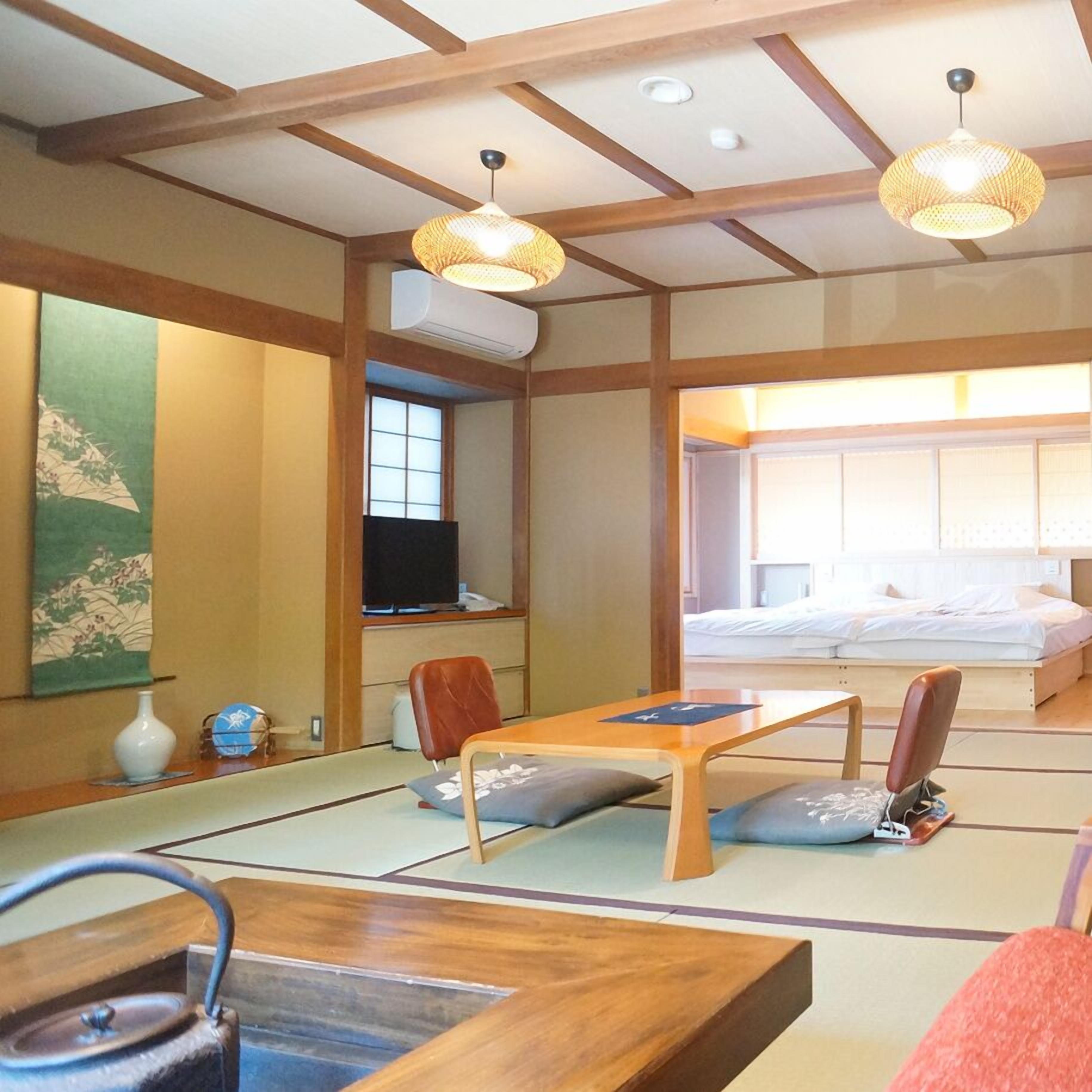 A traditional Japanese room with tatami flooring, a futon bed, a television, and a tea set.