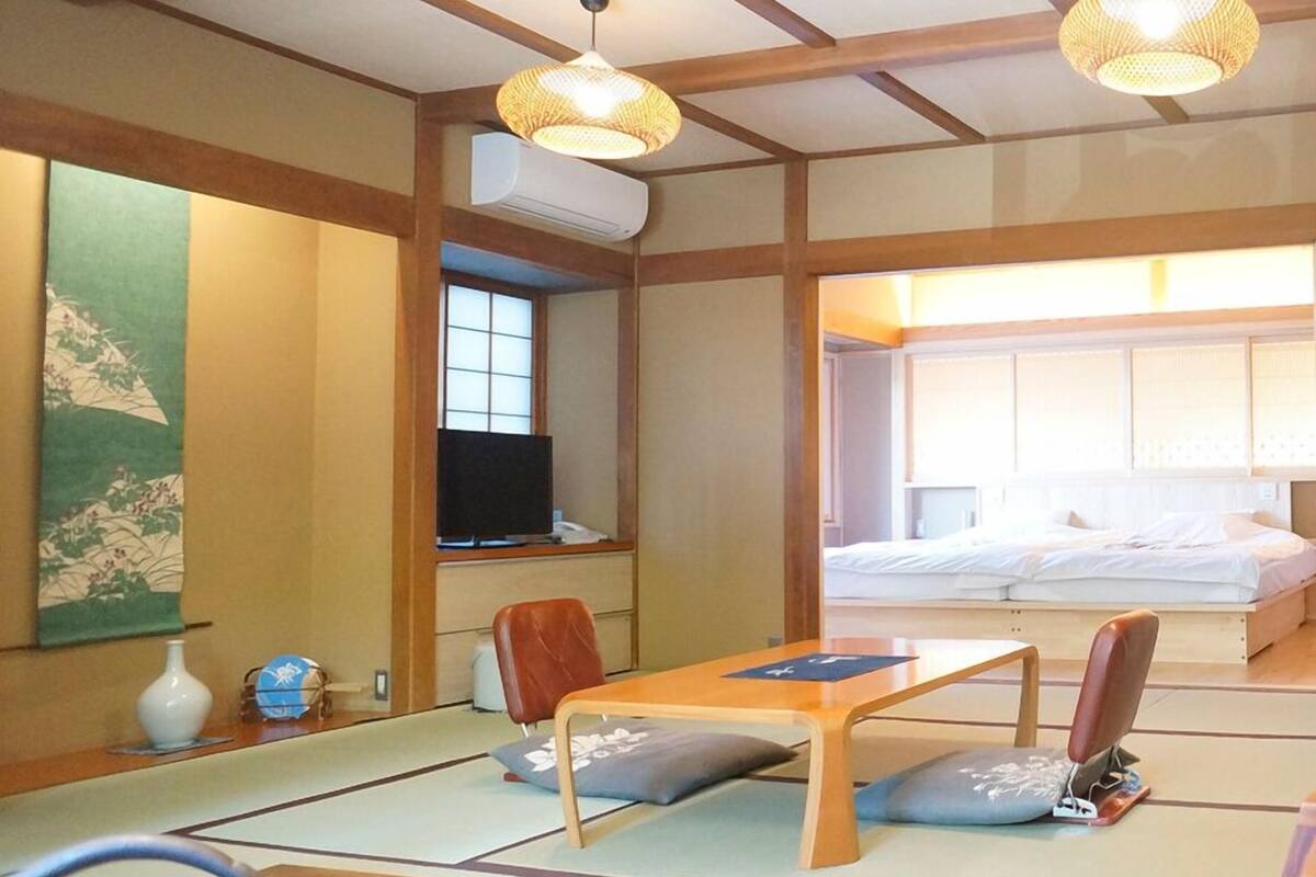 Quarto japonês tradicional com tatames, futon, televisão e um conjunto de chá.