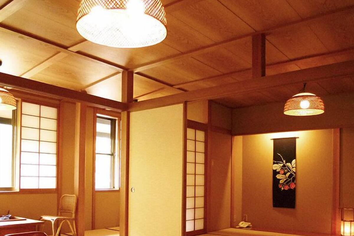 Um quarto japonês tradicional com tatames, uma mesa baixa com um conjunto de chá e portas deslizantes.