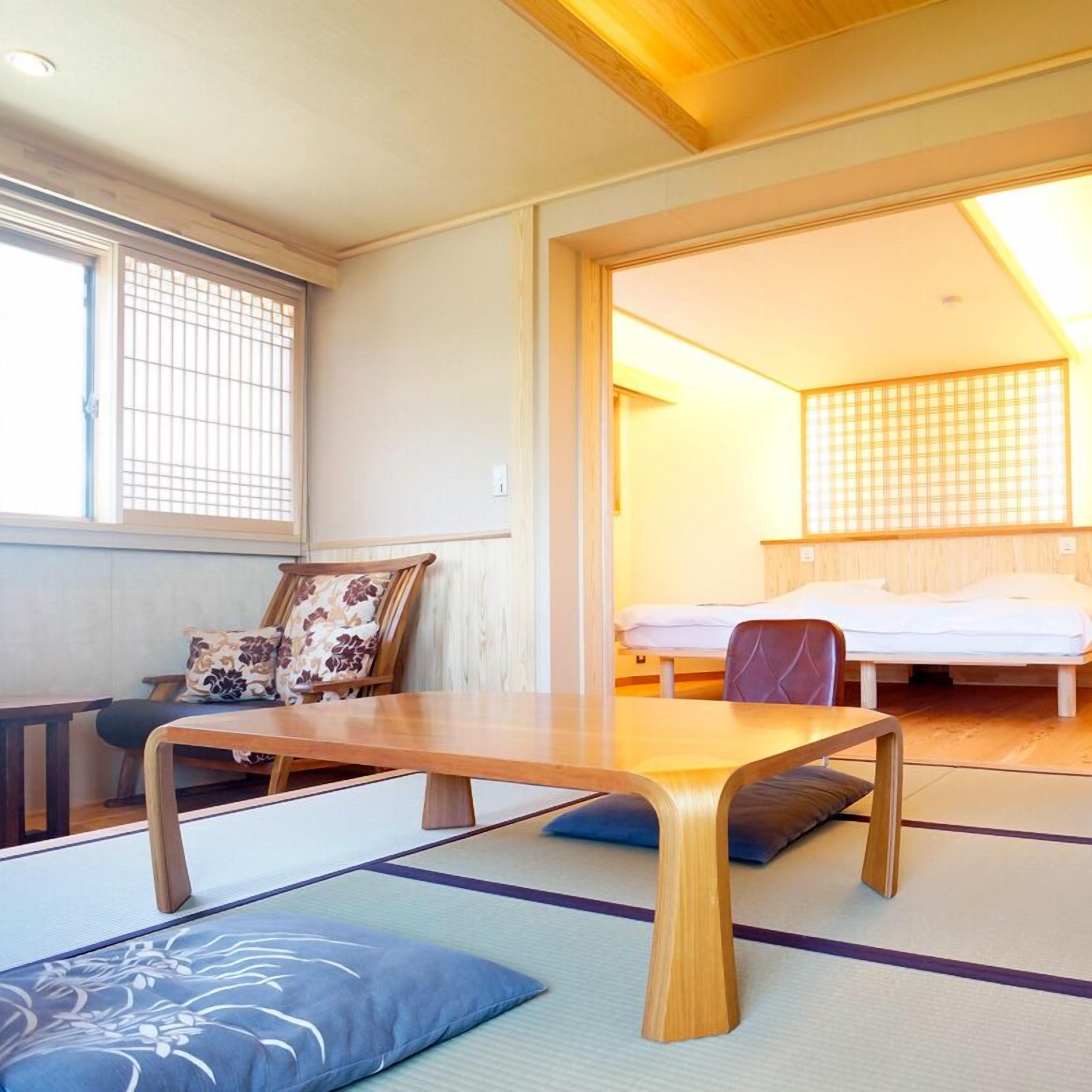 A traditional Japanese room with tatami flooring, a low wooden table, and a futon bed.