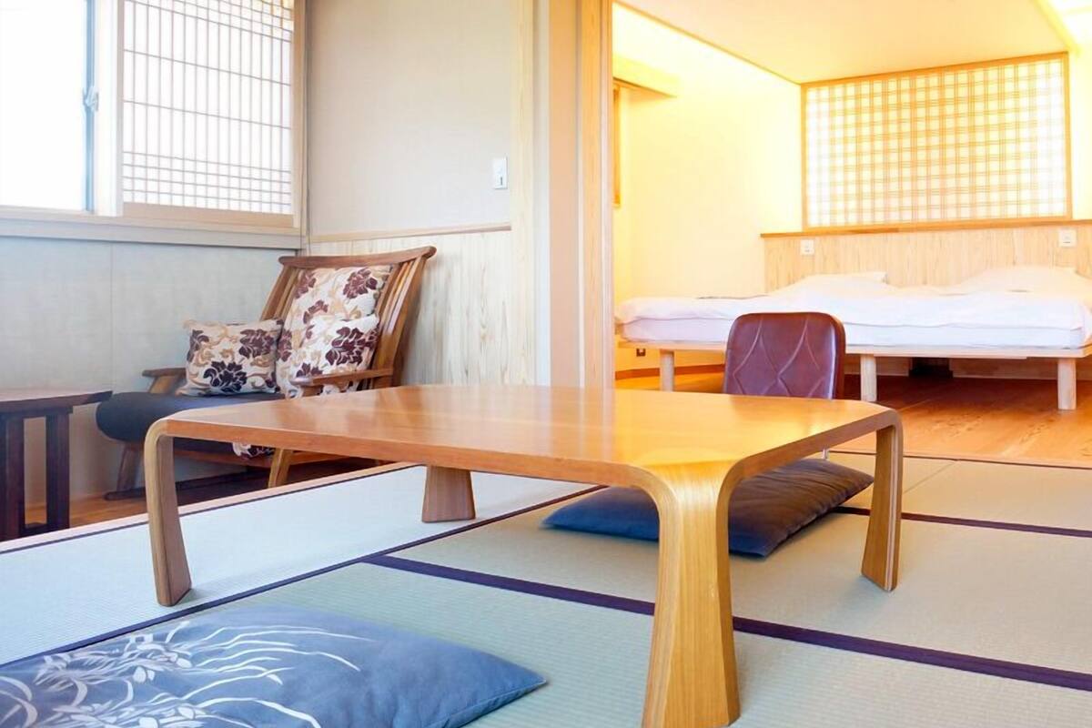 Um quarto em estilo japonês tradicional, com piso de tatame, uma mesa de madeira baixa e uma cama futon.