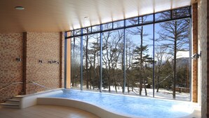 Un jacuzzi moderno en el interior con vistas a un paisaje nevado a través de grandes ventanales.
