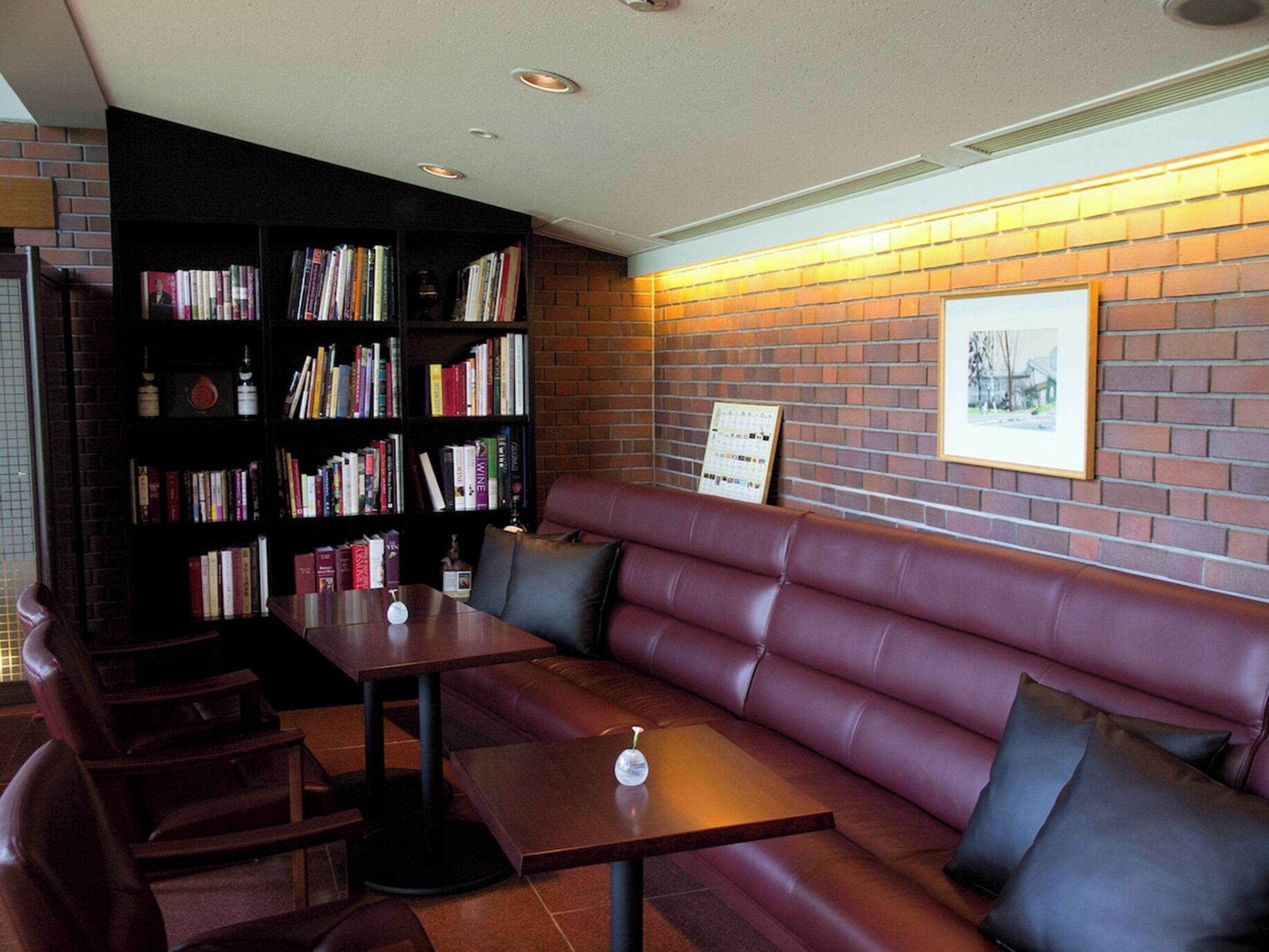 A library with bookshelves, a leather sofa, and a table with a clock.