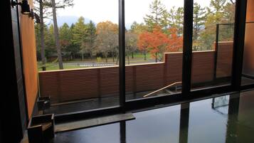 A room with a large window offering a view of trees and a road.
