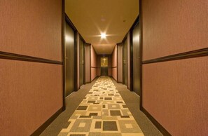 A hotel hallway with a patterned carpet, wooden walls, and a light fixture on the ceiling.