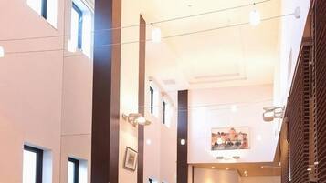 A spacious hotel lobby with high ceilings, large windows, and a central seating area with tables and chairs.