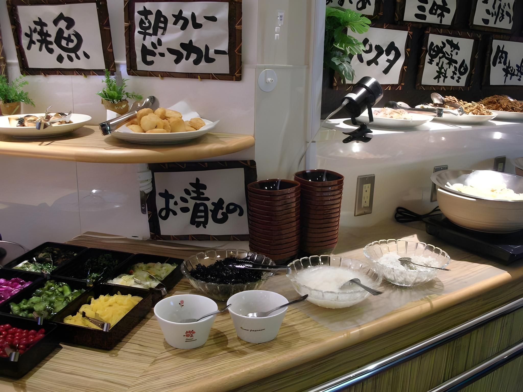Een buffet met diverse gerechten, met Japanse teksten die de verschillende soorten aangeven.