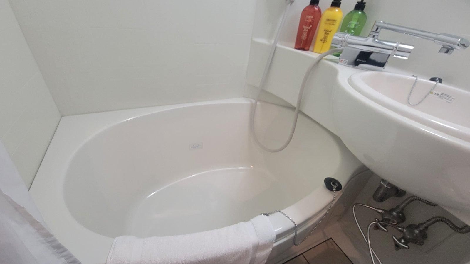 A bathroom with a bathtub, a sink, and toiletries on the wall.