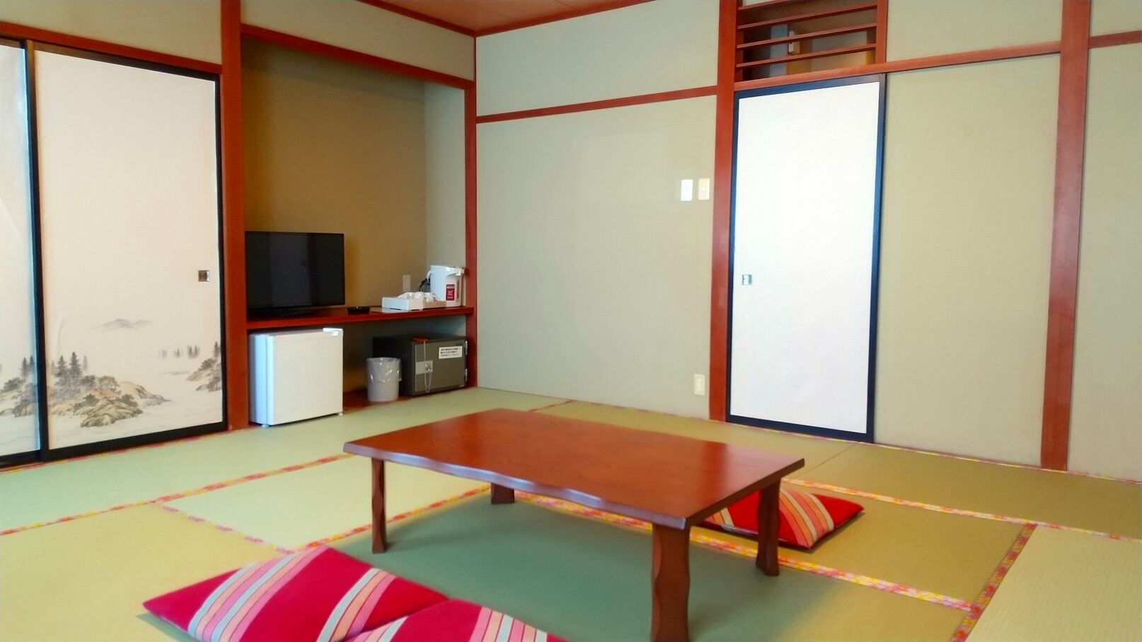 Una habitación japonesa tradicional con suelo de tatami, una mesa de madera baja y puertas correderas.