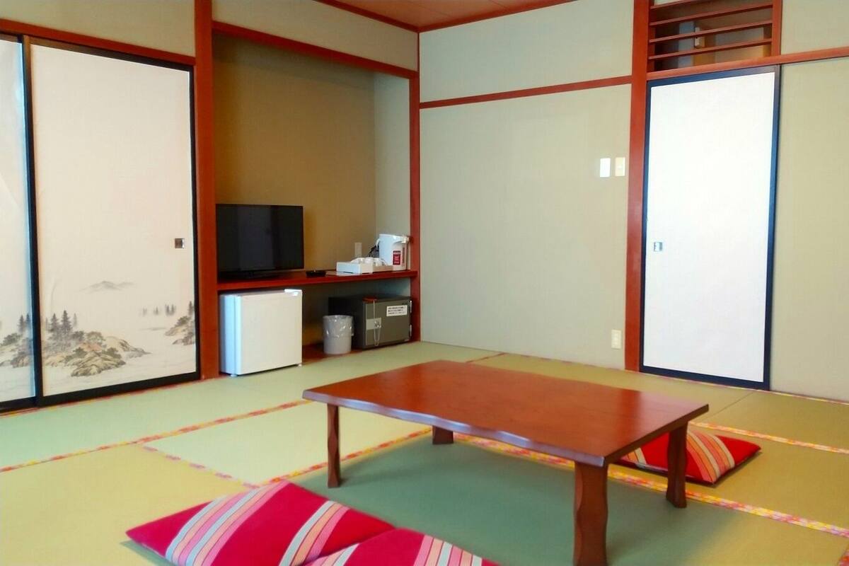 Una habitación japonesa tradicional con suelo de tatami, una mesa de madera baja y puertas correderas.