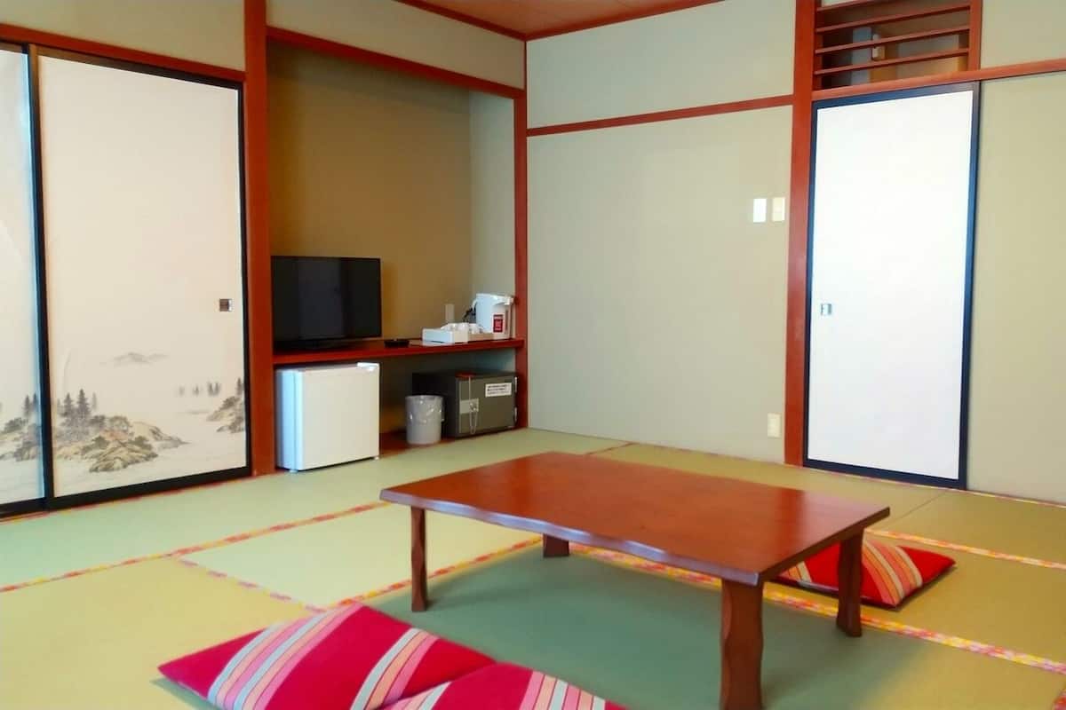 A traditional Japanese room with tatami flooring, a low wooden table, and sliding doors.