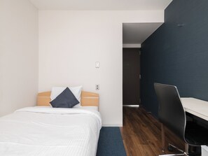 A modern hotel room with a bed, a desk, and a dark-colored wall. - Business Hotel Koyo (Aichi)