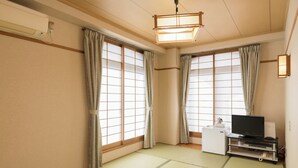 A room with tatami mat flooring, a television on a stand, and a ceiling fan. - Business Hotel Koyo (Aichi)