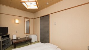 A hotel room with a bed, a desk, a television, a mirror, and a wardrobe. - Business Hotel Koyo (Aichi)