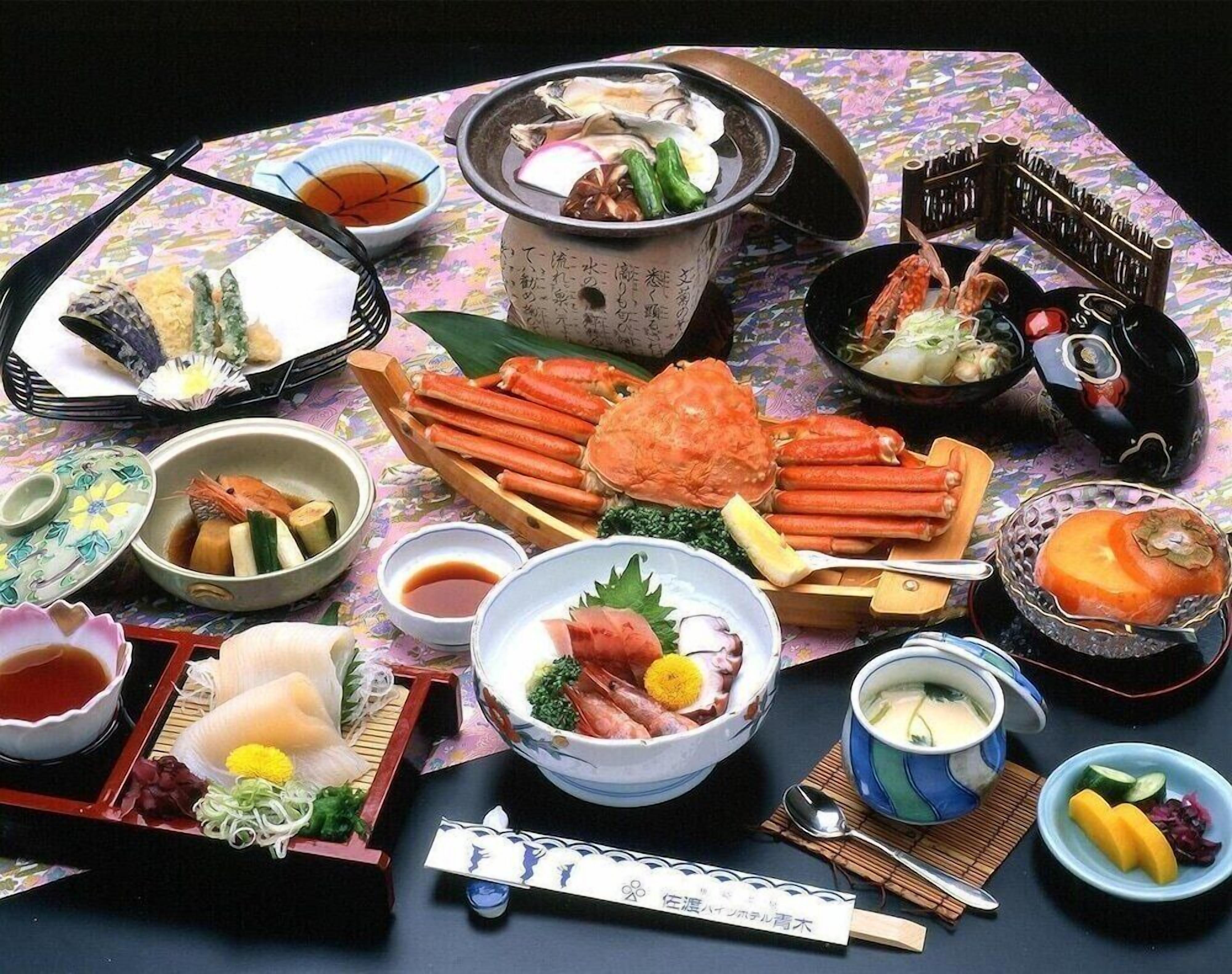 A variety of Japanese dishes including seafood, vegetables, and tofu, served on a table with chopsticks and small bowls.