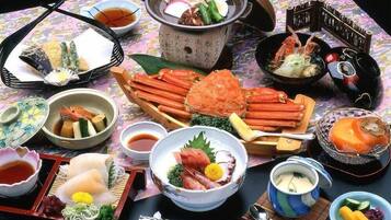 A variety of Japanese dishes including seafood, vegetables, and tofu, served on a table with chopsticks and small bowls.