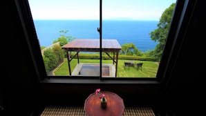A room with a large window overlooking a garden and the sea. - Seaside Resort Tsukino Usagi (Ito)