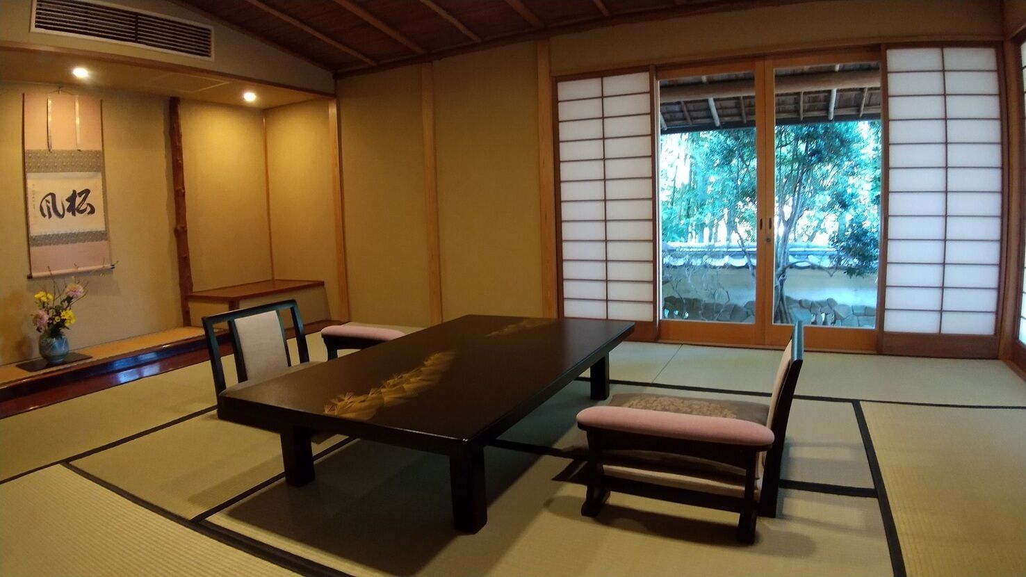 A traditional Japanese room with tatami flooring, a low table, and sliding doors.