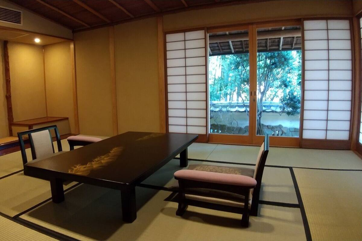 Um quarto japonês tradicional com tatames, uma mesa baixa e portas deslizantes.